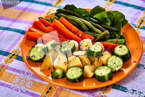 Image of Ladle of steamed freshly harvested young vegetables including crinkle cut sliced carrots, peas and potato batons