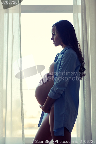 Image of happy pregnant woman with big bare tummy at home