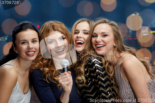 Image of happy young women with microphone singing karaoke