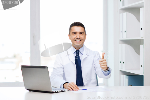 Image of smiling doctor showing thumbs up in medical office