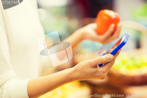 Image of woman with smartphone and persimmon in market