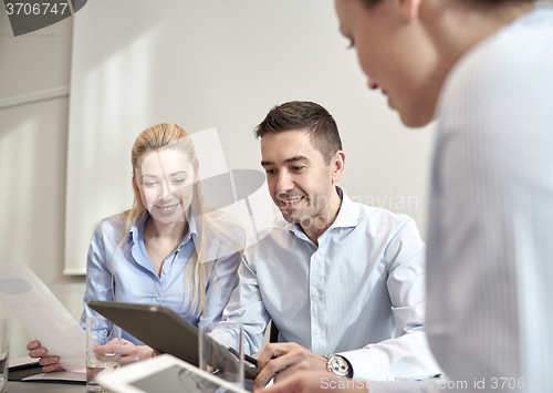 Image of smiling businesspeople with tablet pc in office