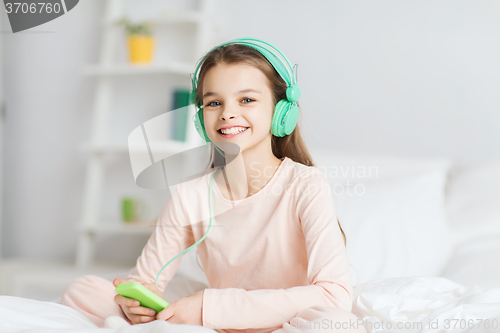 Image of girl sitting on bed with smartphone and headphones