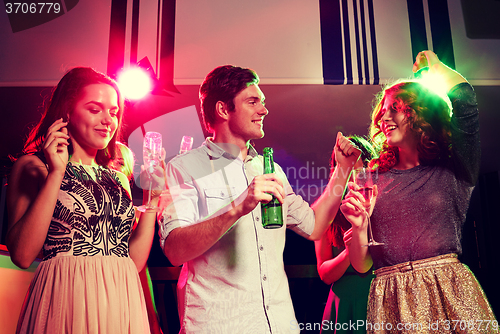 Image of smiling friends with wine glasses and beer in club