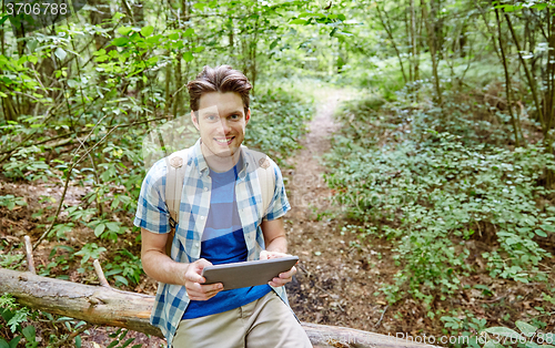 Image of happy man with backpack and tablet pc in woods