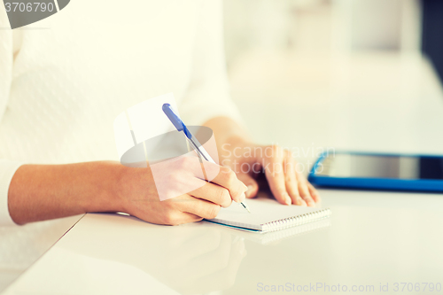 Image of close up of hands with pen writing to notepad