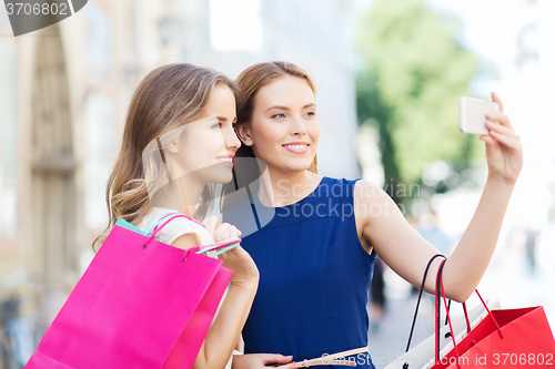 Image of happy women with shopping bags and smartphone