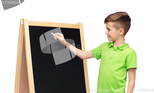 Image of happy boy with chalk and blank school blackboard