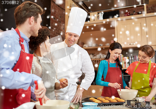 Image of happy friends and chef cook baking in kitchen