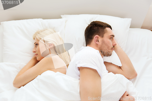 Image of unhappy couple lying in bed at home