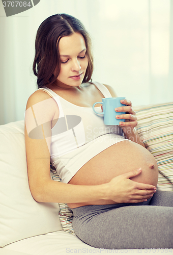 Image of happy pregnant woman with cup drinking tea at home