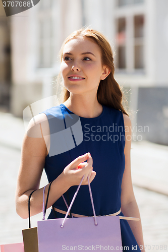 Image of happy woman with shopping bags walking in city 