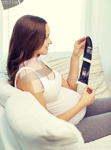 Image of happy pregnant woman with ultrasound image at home