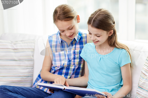 Image of two happy girls reading book at home