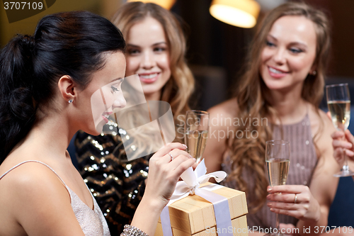 Image of happy women with champagne and gift at night club