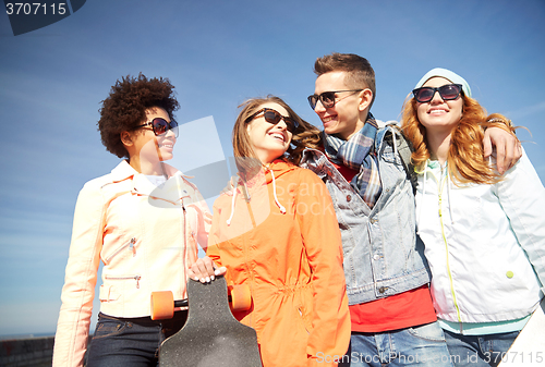 Image of happy teenage friends in shades talking on street