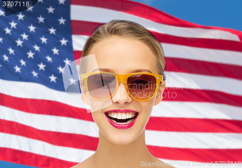 Image of happy young woman in sunglasses over american flag