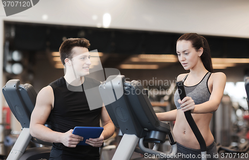 Image of woman with trainer exercising on stepper in gym