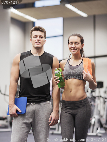 Image of happy couple in gym with water and tablet pc