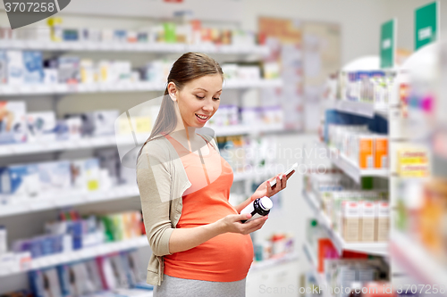 Image of happy pregnant woman with smartphone at pharmacy