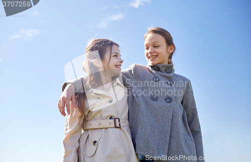 Image of happy little girls hugging and talking outdoors