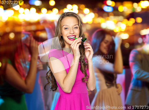 Image of happy young woman or teen girl with party horn