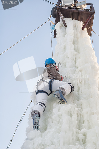 Image of Girl climbs upward on ice climbing competition