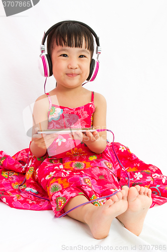 Image of Chinese little girl on headphones holding mobile phone