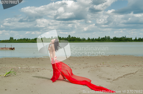 Image of Attractive naked girl with red scarf on sand