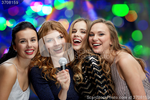 Image of happy young women with microphone singing karaoke