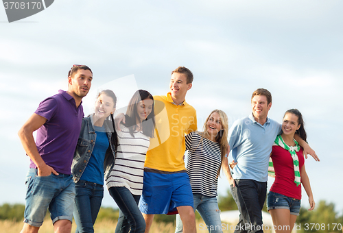 Image of group of happy friends walking along beach