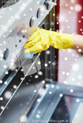 Image of close up of woman cleaning oven at home kitchen