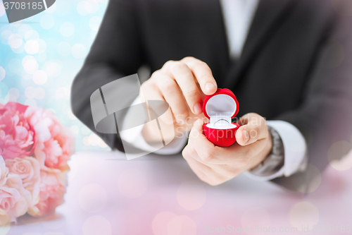 Image of close up of man with gift box and engagement ring