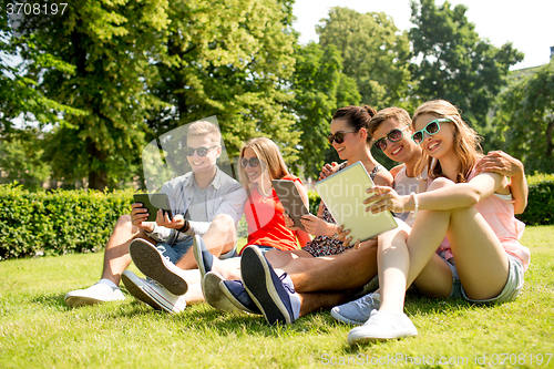 Image of smiling friends with tablet pc computers in park