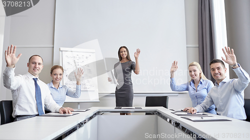 Image of group of businesspeople waving hands in office