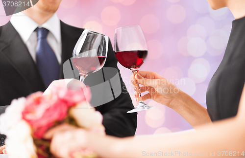 Image of happy engaged with flowers clinking wine glasses