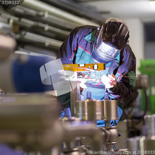 Image of Industrial worker welding in metal factory.