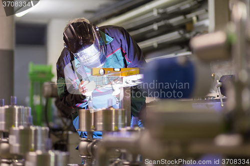 Image of Industrial worker welding in metal factory.