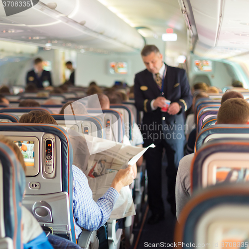 Image of Steward and passengers on commercial airplane.