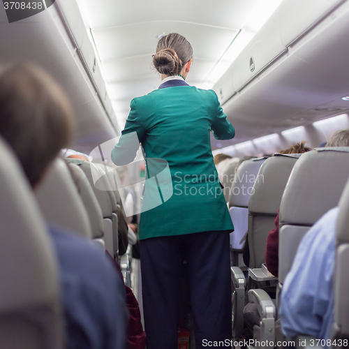 Image of Stewardessand passengers on commercial airplane.