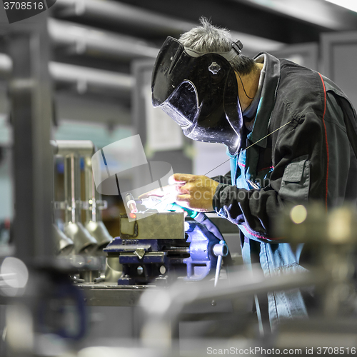 Image of Industrial worker welding in metal factory.