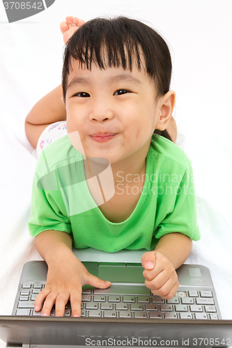 Image of Chinese little girl lying down with laptop