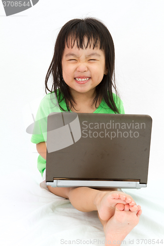 Image of Chinese little girl sitting on floor with laptop