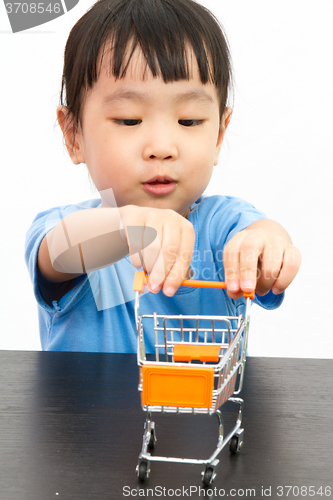 Image of Chinese little girl pushing a toy shopping cart