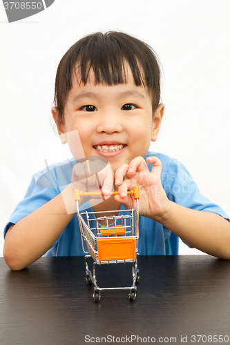 Image of Chinese little girl pushing a toy shopping cart