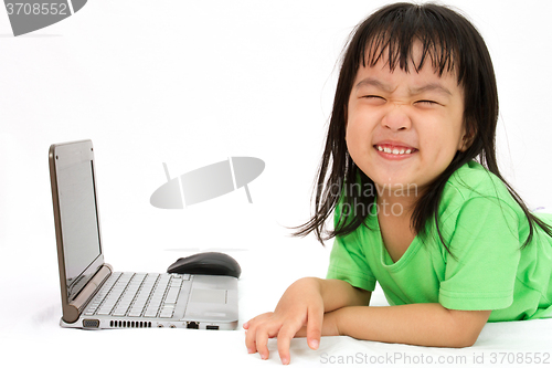 Image of Chinese little girl lying down with laptop