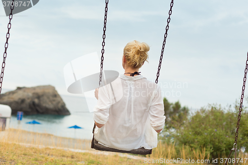 Image of Young blonde woman sitting on the swing