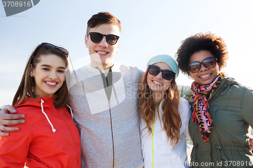 Image of happy teenage friends in shades hugging outdoors