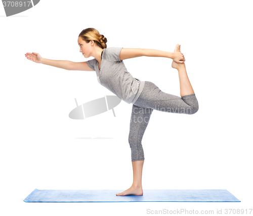 Image of woman making yoga in lord of the dance pose on mat