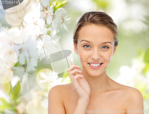 Image of happy young woman applying cream to her face